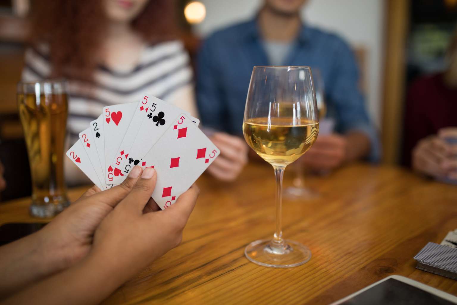 Leute spielen Karten und trinken Wein.