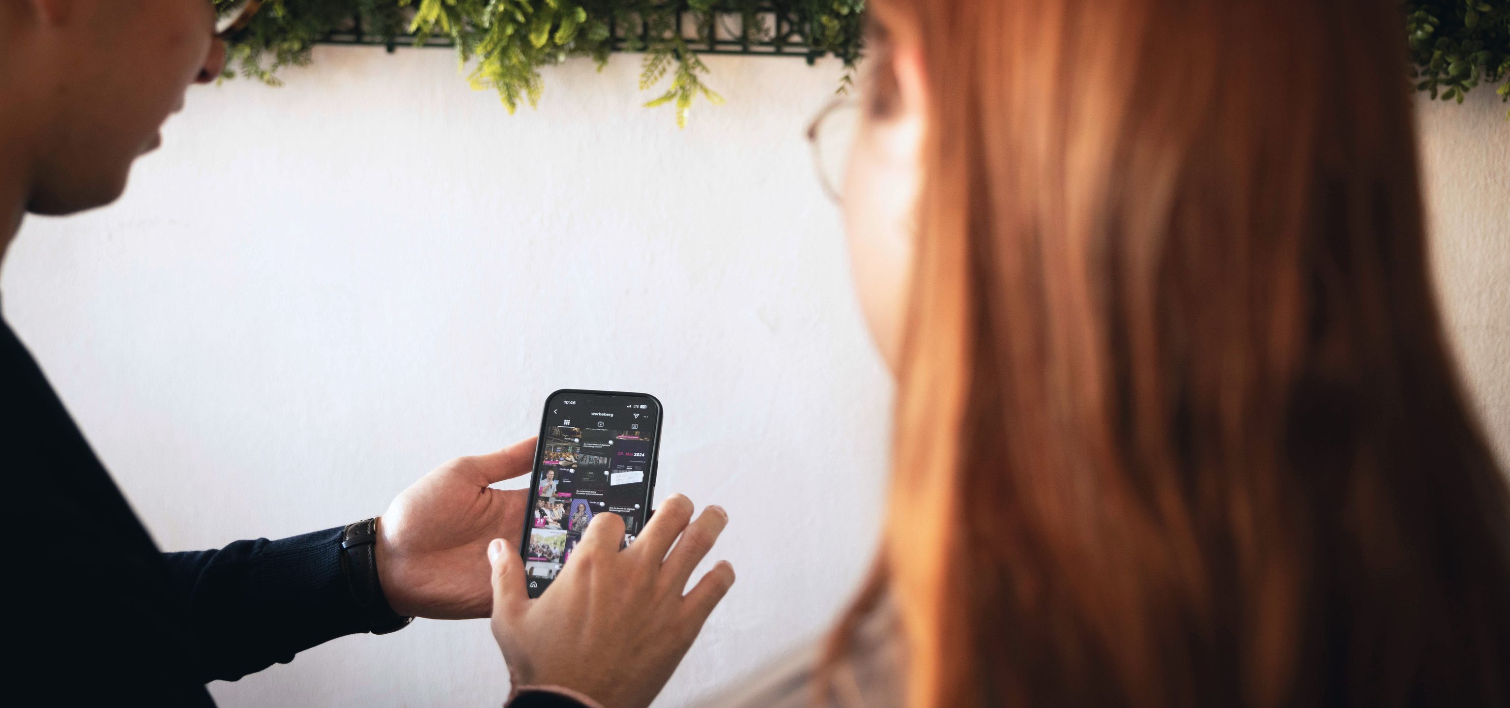 Eine Person hält ein Handy in der Hand und redet mit einem Gesprächspartner