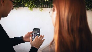 Eine Person hält ein Handy in der Hand und redet mit einem Gesprächspartner