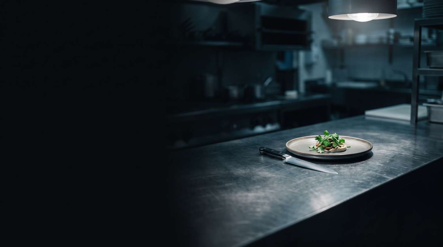 Angerichteter Teller auf dem Pass einer dunklen Restaurantküche