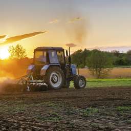 Traktor bei der Feldarbeit im Sonnenuntergang