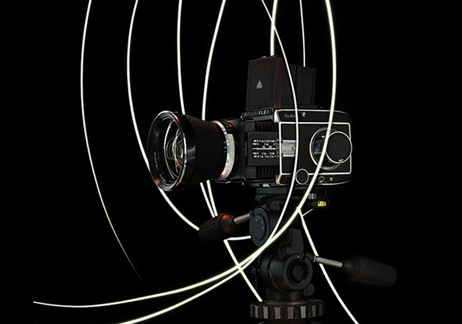 Image réalisée chez Dahinden, montrant un appareil rolleiflex, sur fond noir, entouré d'un halo lumineux tournoyant.