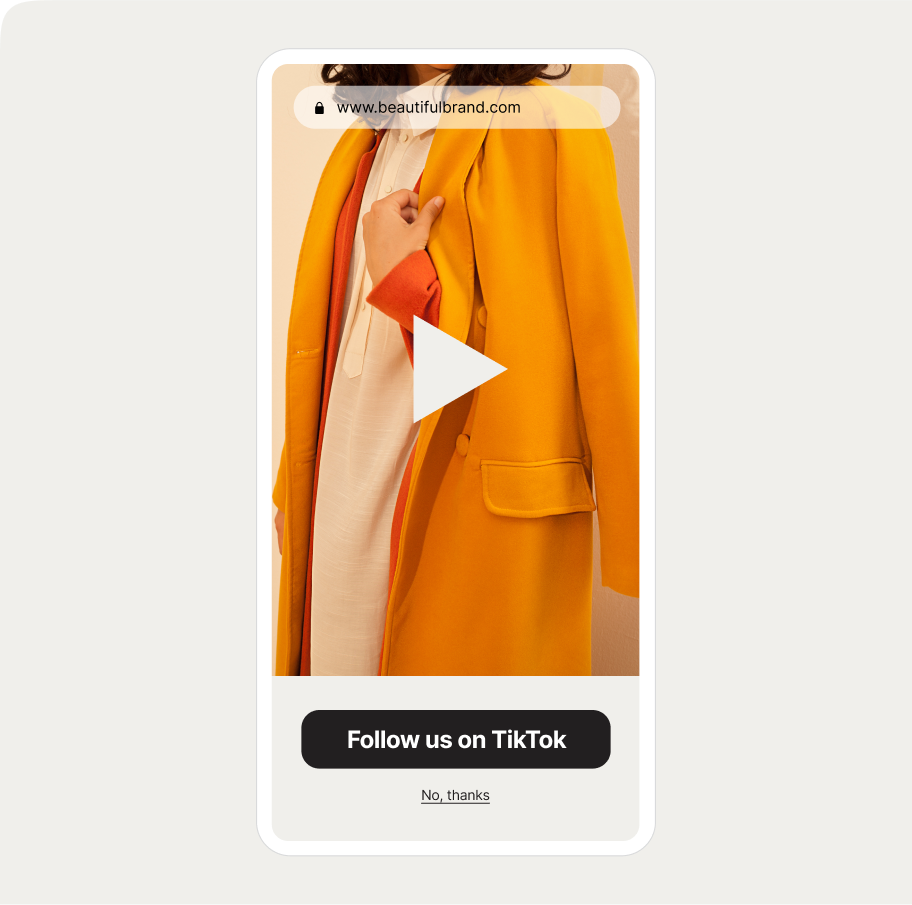 mobile popup with a embeded video displaying a yellow coat over a white outfit. Website URL at top, "Follow us on TikTok" button below.