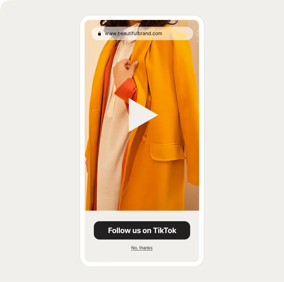 mobile popup with a embeded video displaying a yellow coat over a white outfit. Website URL at top, "Follow us on TikTok" button below.