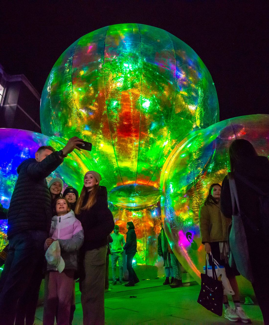 A family take a selfie in front of illuminated transluncent giant balls