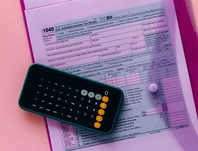 Figuring out remote work taxes with a phone calculator on top of an envelope containing the IRS Form 1040
