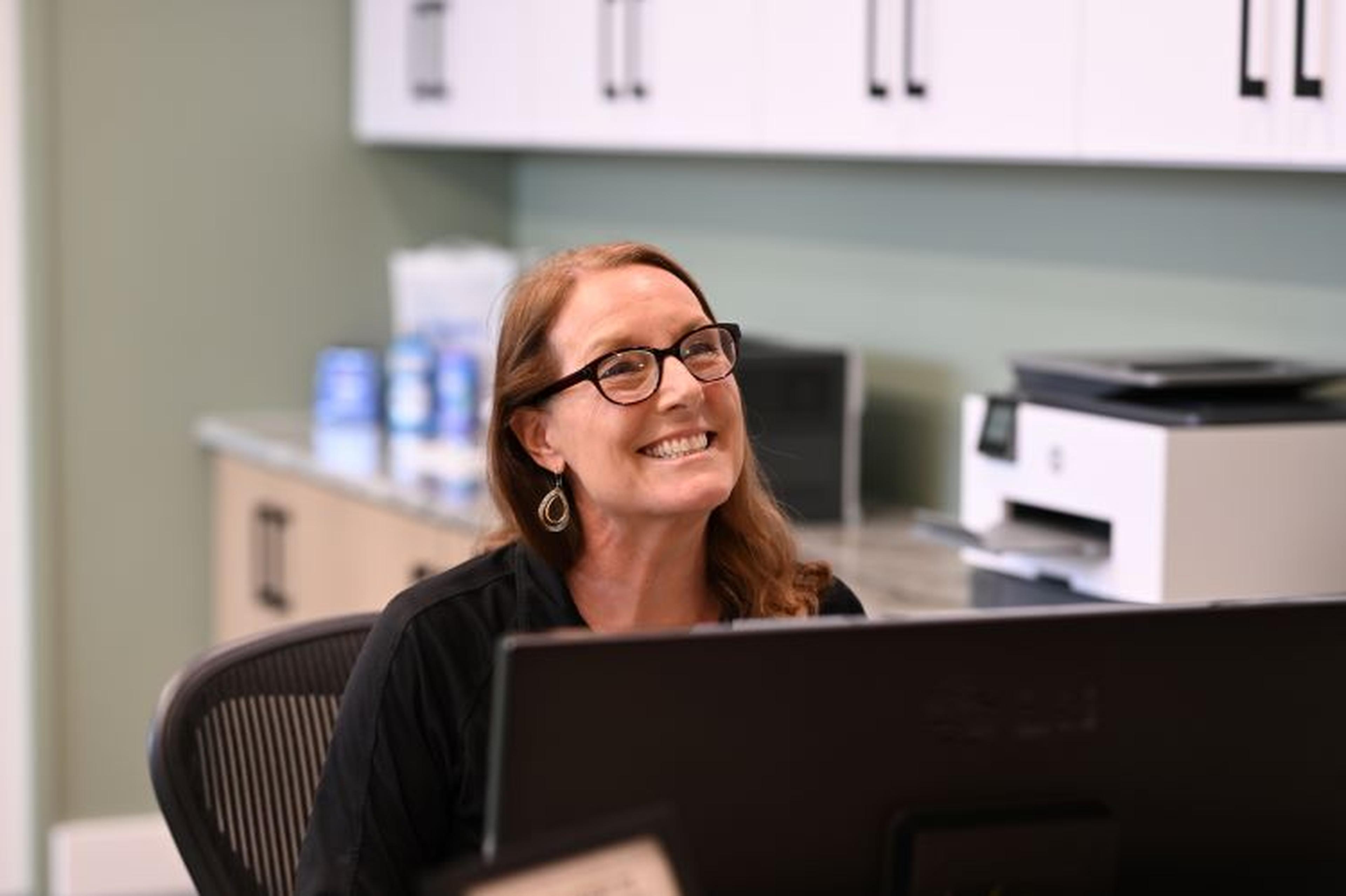 A woman smiling while sitting at the front desk