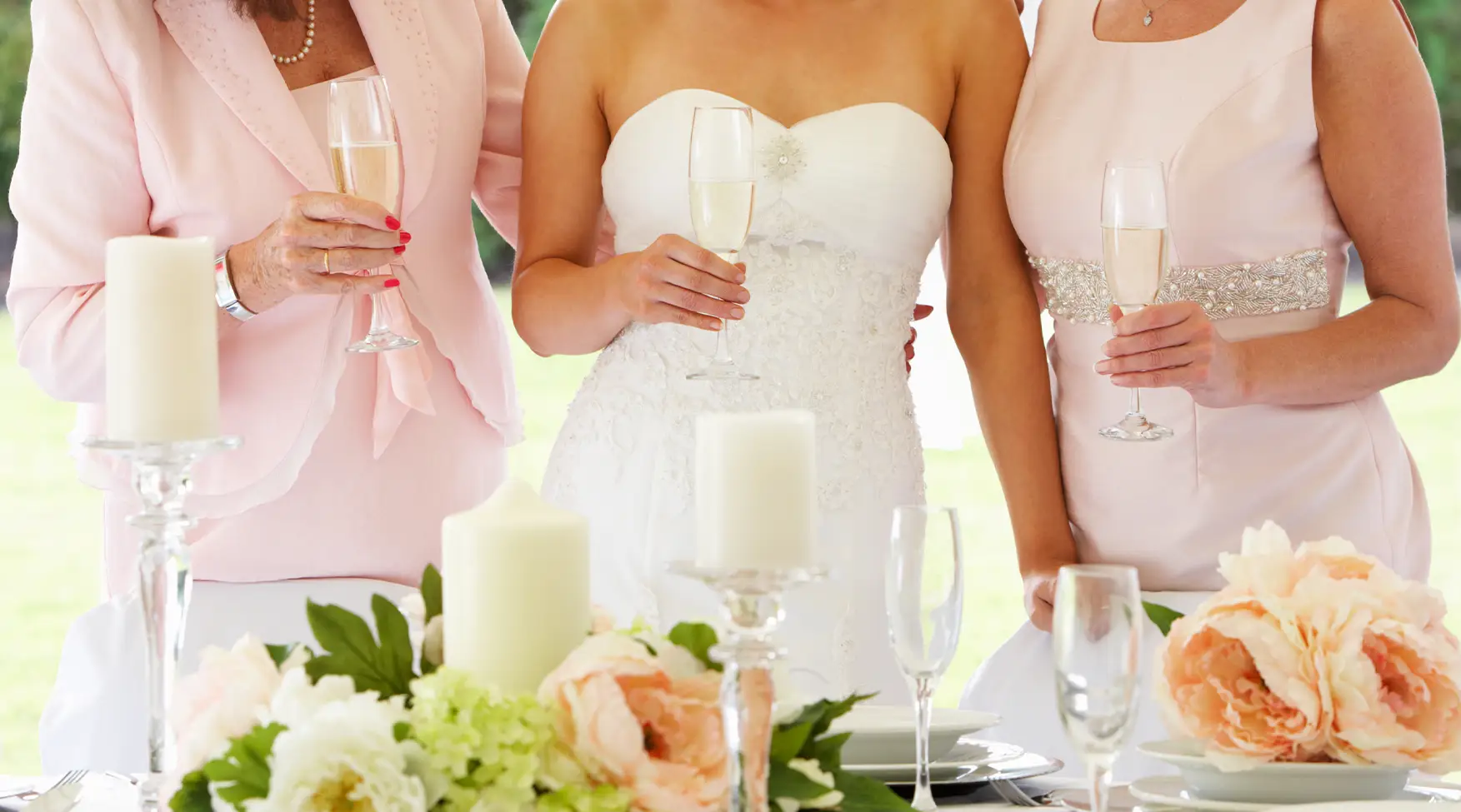 Bruid met bruidsmoeder en bruidsmeisje en een glas champagne. Gekleurde kleding