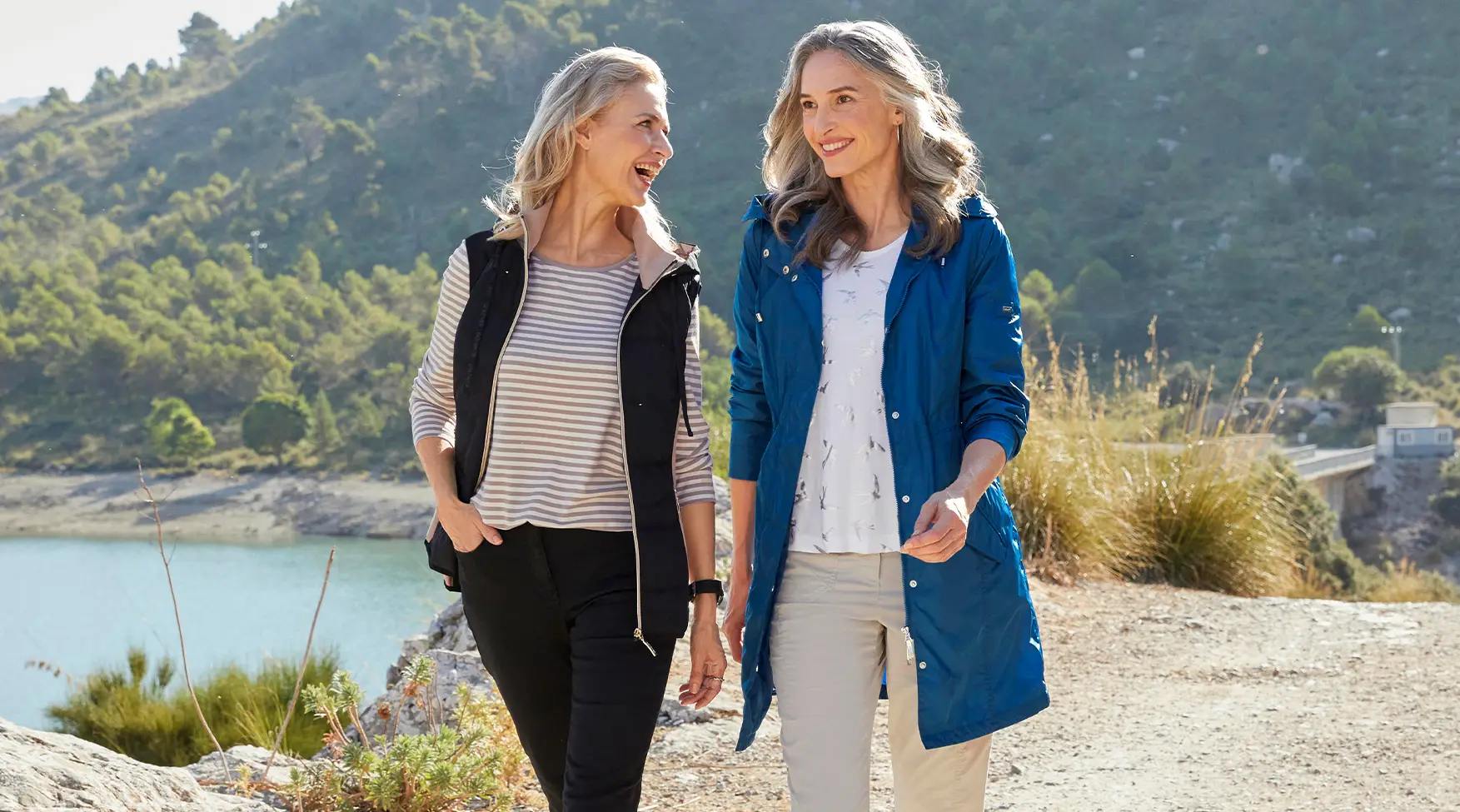 Magazinbeitrag: sportlich elegante Mode | Zwei Frauen laufen an einem See entlang 