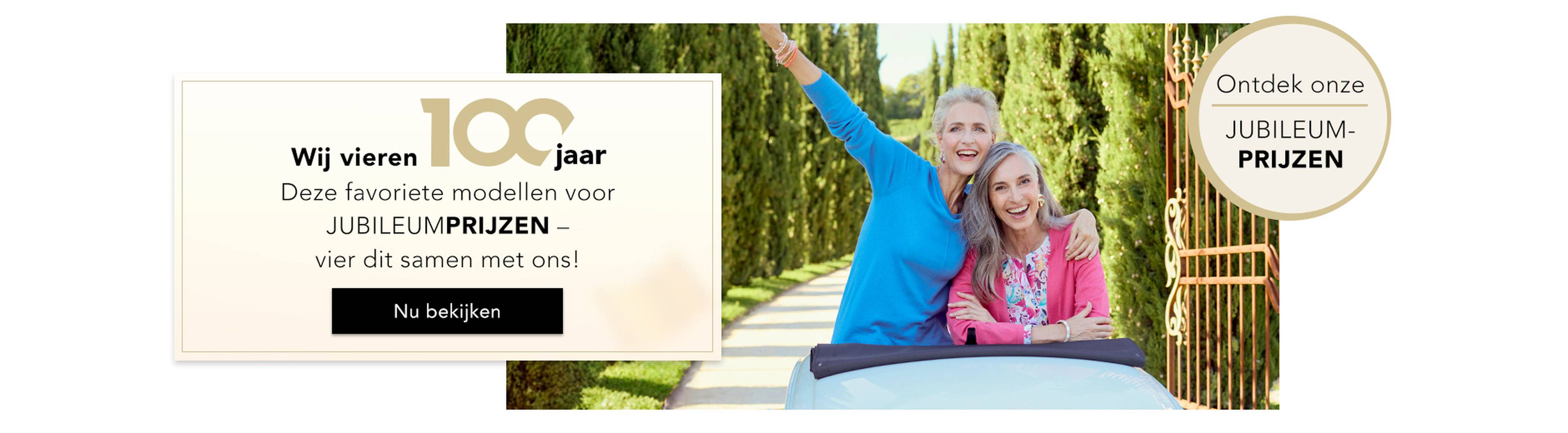  Een groep vrouwen viert vrolijk feest in chique outfits; op een spandoek staat „100 jaar“ en „JUBILEUMPRIJZEN“.