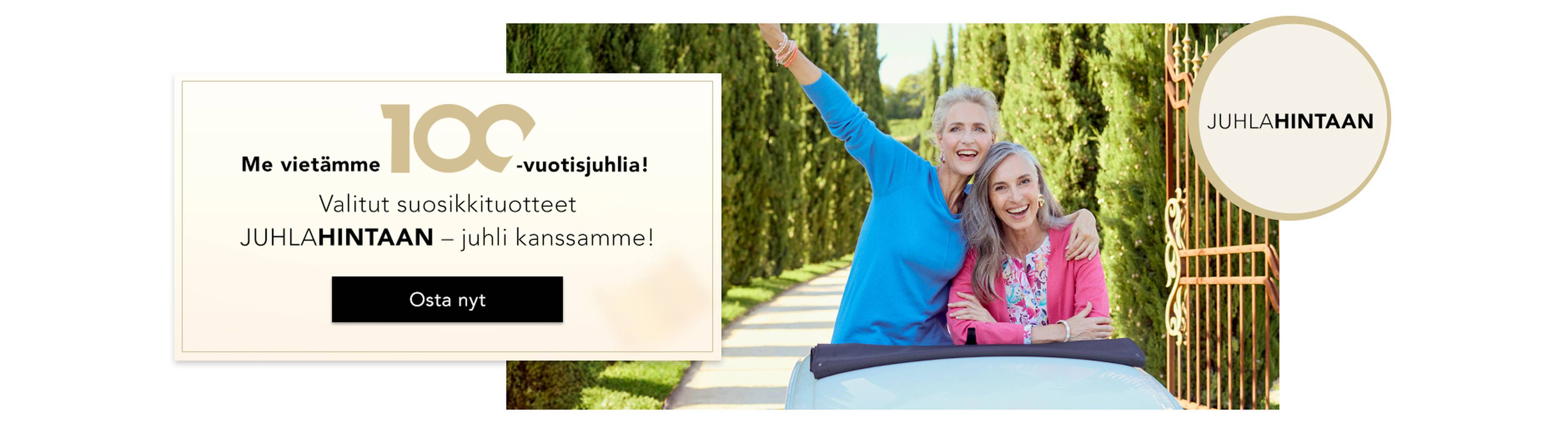  Ryhmä naisia juhlii iloisesti tyylikkäissä asuissa; banderollissa lukee ”100 vuotta” ja ”JUHLAHINNAT”.