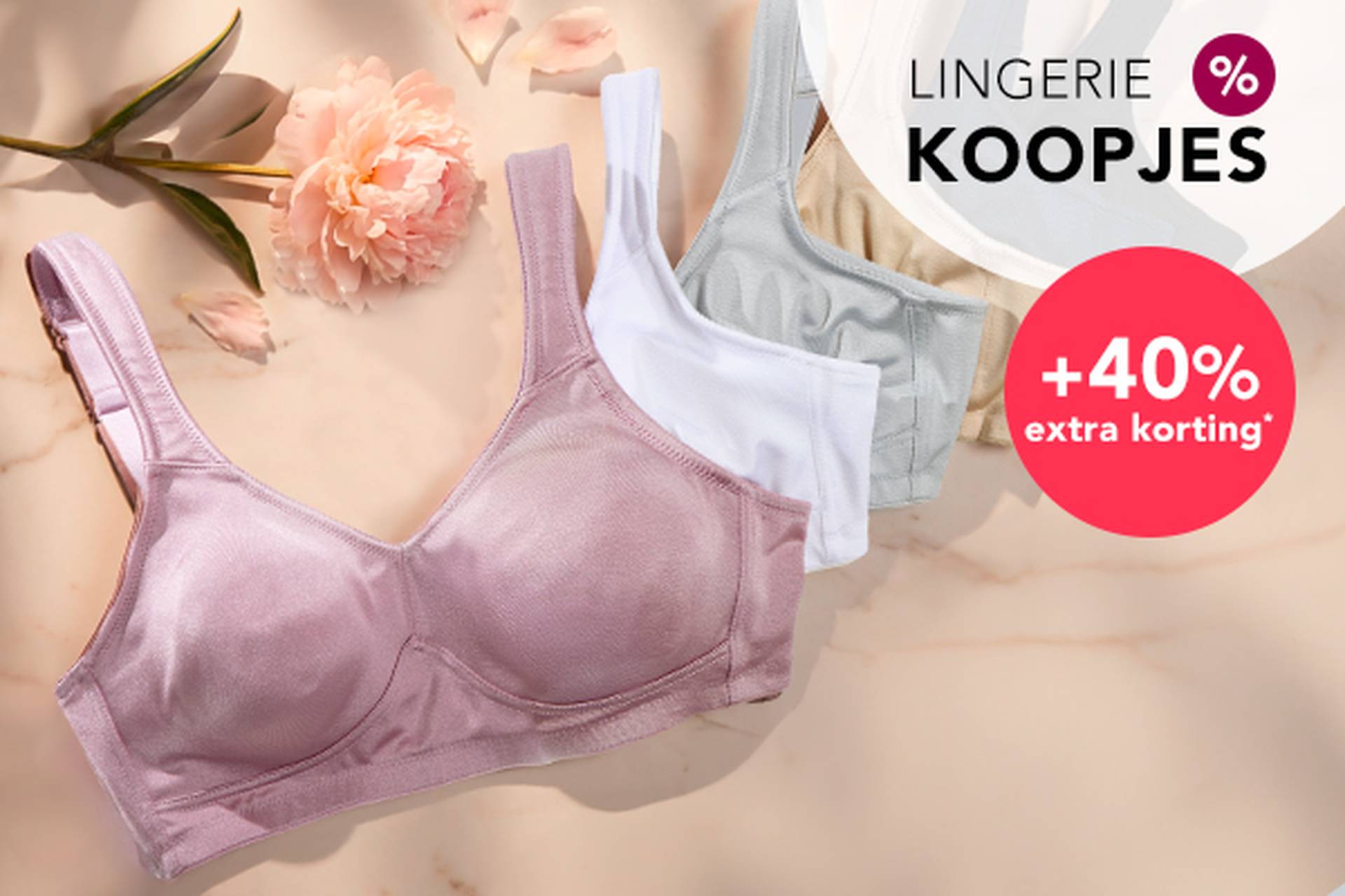  Drie beha’s in zachte kleuren liggen op een ondergrond, met daarnaast een bloem. In de aanbiedingstekst wordt gewezen op kortingen tot 70% en nog eens 20% extra korting.
