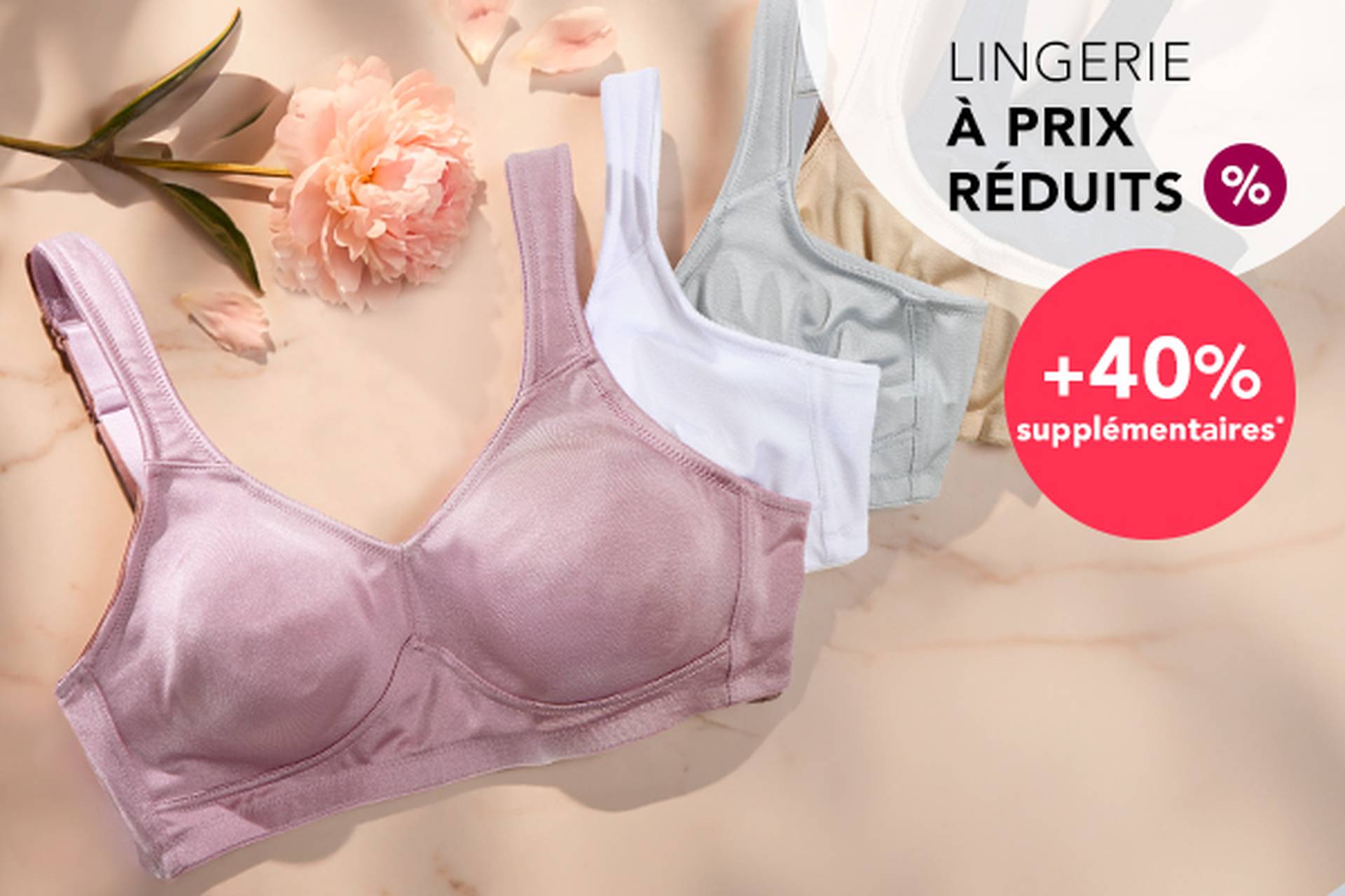  Trois soutiens-gorge aux couleurs douces posés sur une surface, accompagnés d'une fleur. Le texte promotionnel met en avant des réductions allant jusqu'à 70 % et une remise supplémentaire de 20 %.