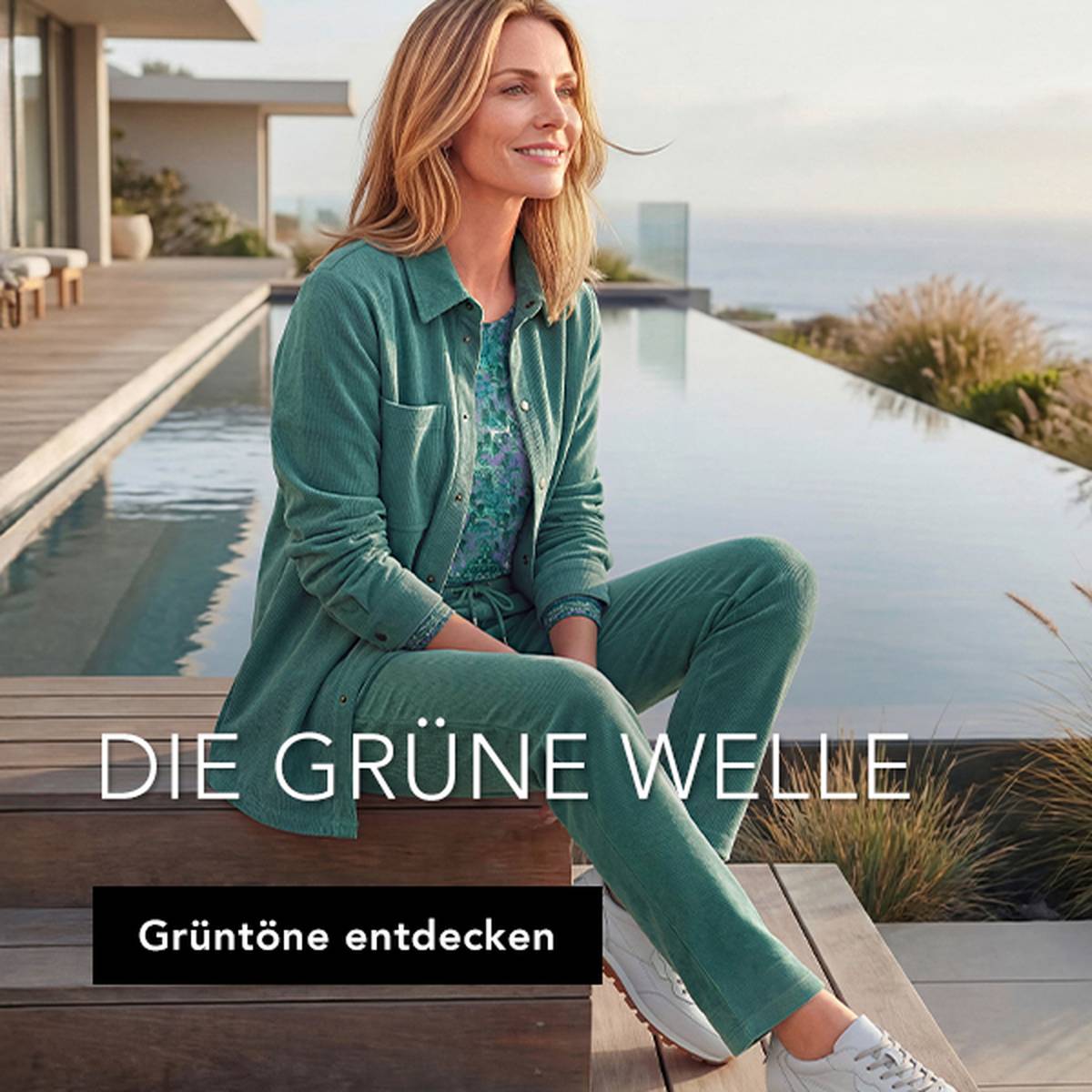 Eine Frau in einer burgunderroten Steppjacke und einer grauen Hose geht im Freien spazieren, im Hintergrund sind herbstliche Bäume zu sehen.