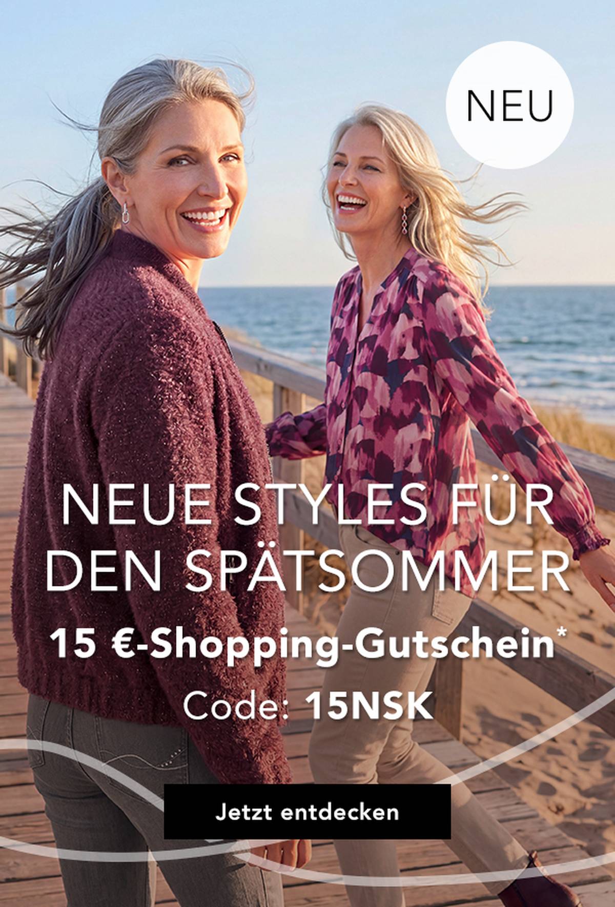  Zwei Frauen spazieren auf einer Strandpromenade in der Nähe des Strandes, lächeln und tragen schicke Outfits. Über dem Bild ist ein Werbetext auf Deutsch eingeblendet.