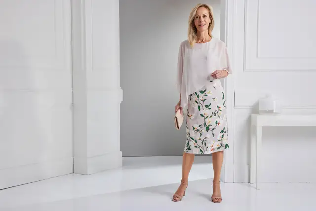 Frau im eleganten floralen Kleid in hellrosa in einem weißen eleganten Raum