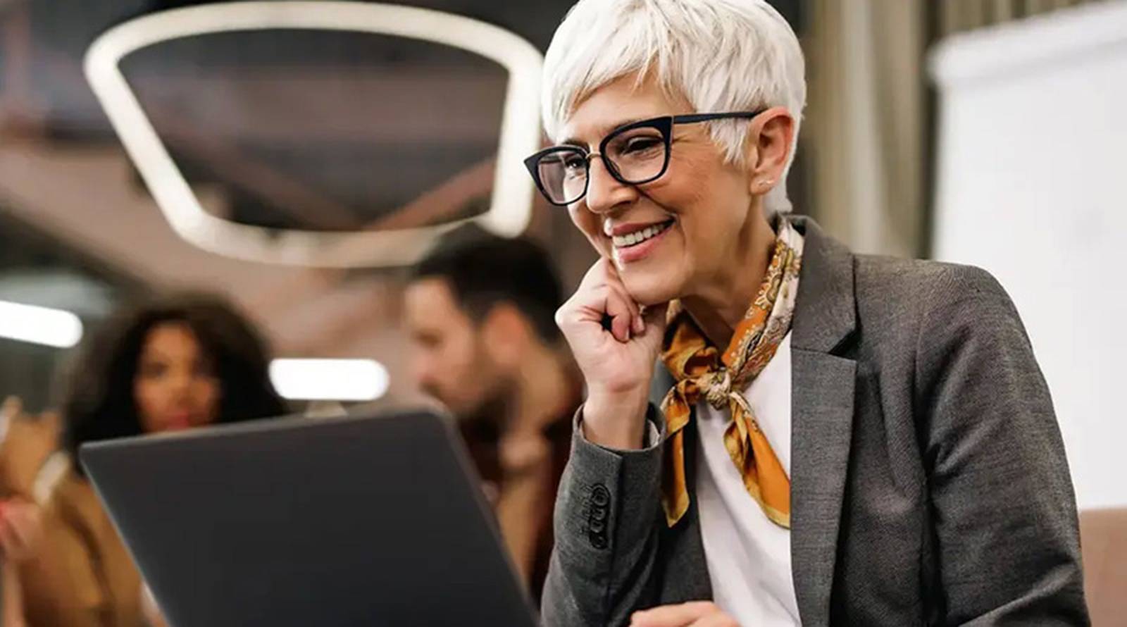 Liikemuoti yli 50-vuotiaille naisille - kuva vanhemmasta naisesta muistikirjan ääressä 