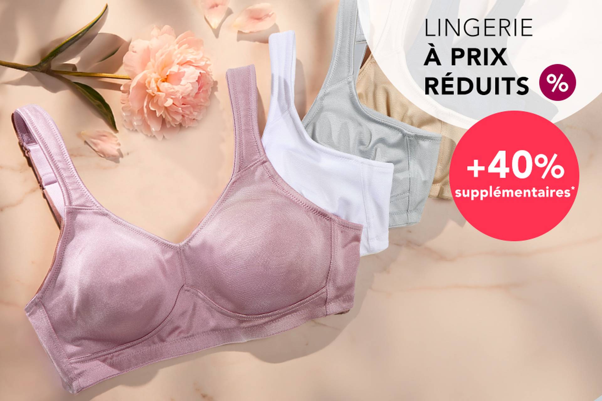  Trois soutiens-gorge aux couleurs douces posés sur une surface, accompagnés d'une fleur. Le texte promotionnel met en avant des réductions allant jusqu'à 70 % et une remise supplémentaire de 20 %.