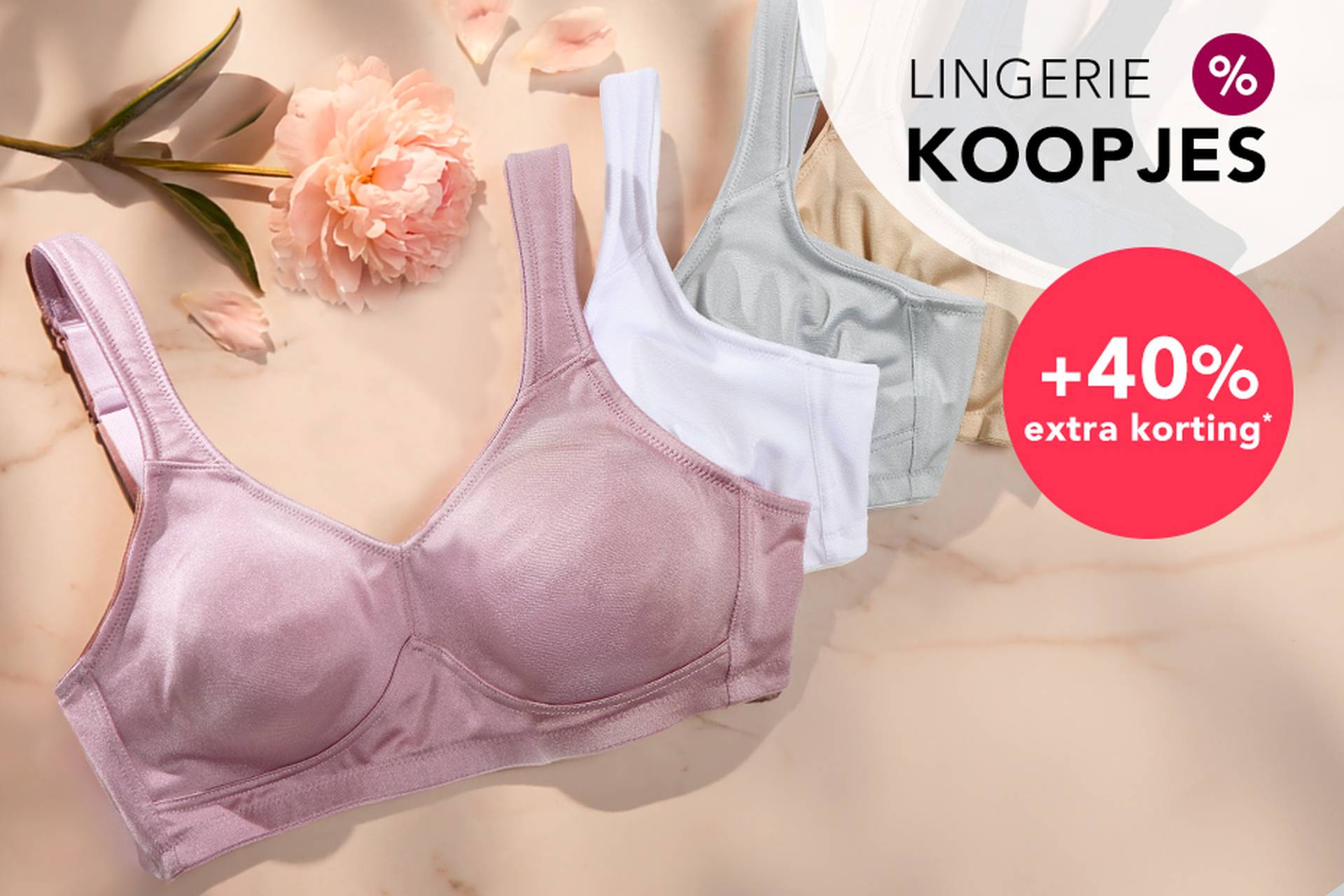  Drie beha’s in zachte kleuren liggen op een ondergrond, met daarnaast een bloem. In de aanbiedingstekst wordt gewezen op kortingen tot 70% en nog eens 20% extra korting.