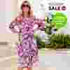  Eine Frau in einem farbenfrohen Blumenkleid und mit Sonnenbrille, die draußen vor einem grünen Hintergrund steht. Auf dem Bild sind Schilder mit „Sale“-Aufschriften zu sehen.