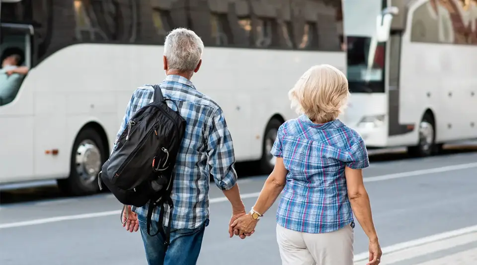 Magazinbeitrag: Die Busreise | Frau und Mann Hand in Hand vor einem Bus laufend