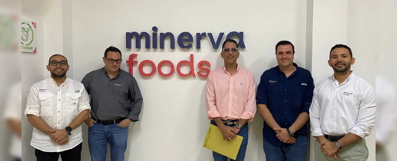 Five men standing in front of a wall with the "Minerva Foods" logo, wearing casual business attire and smiling.