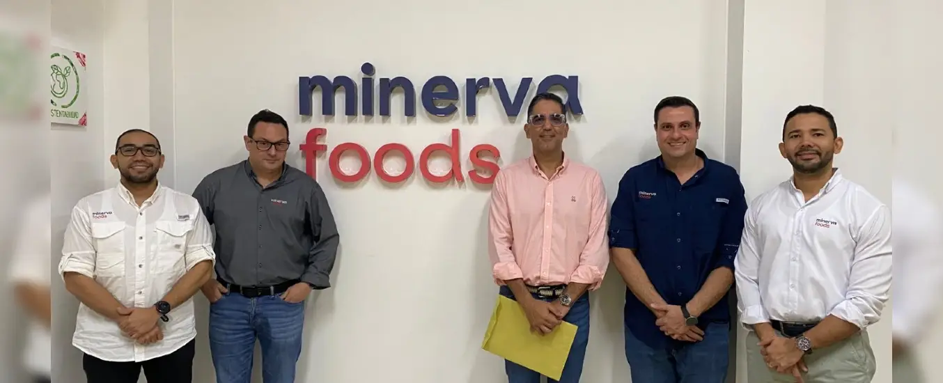 Five men standing in front of a wall with the "Minerva Foods" logo, wearing casual business attire and smiling.