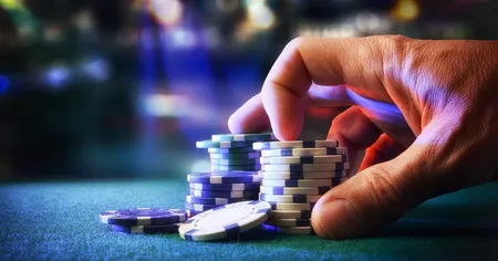 A hand pushing stacks of blue, green, and white chips