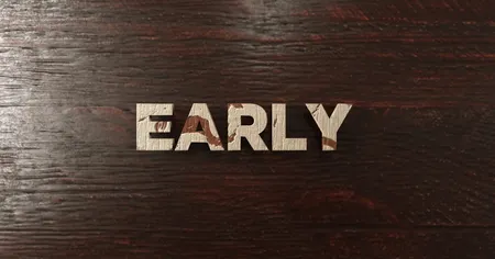 Wooden letters spelling "EARLY" placed on a dark wooden surface.