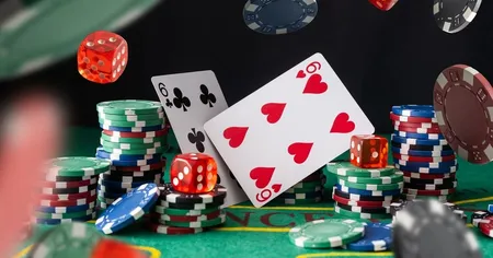 Poker chips, red dice, and playing cards, including the 6 of clubs and 6 of hearts, scattered on a green casino table.