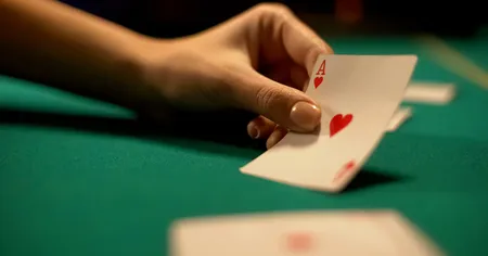 A hand holding Ace of Heart with a green felt in the background
