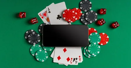 Bài poker, chip, xúc xắc và điện thoại di động đặt trên mặt nỉ xanh.