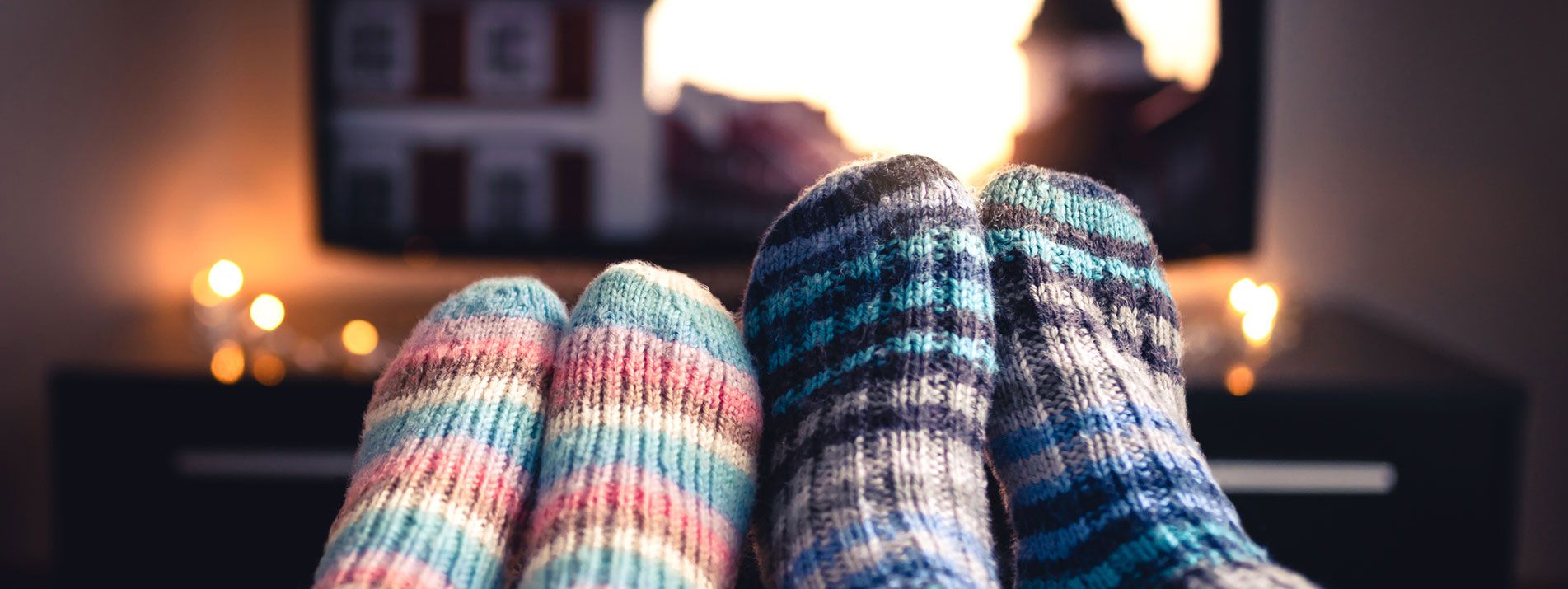 Två par fötter med raggsockar på framför en tv