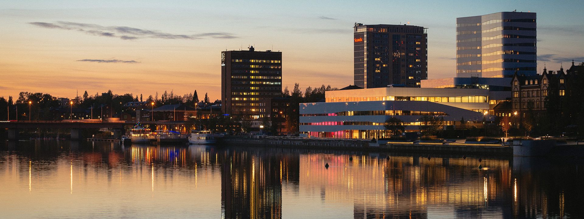 Umeå stad i skymningen. Man ser älven, tegsbron, thulehuset, väven och rådhuset.