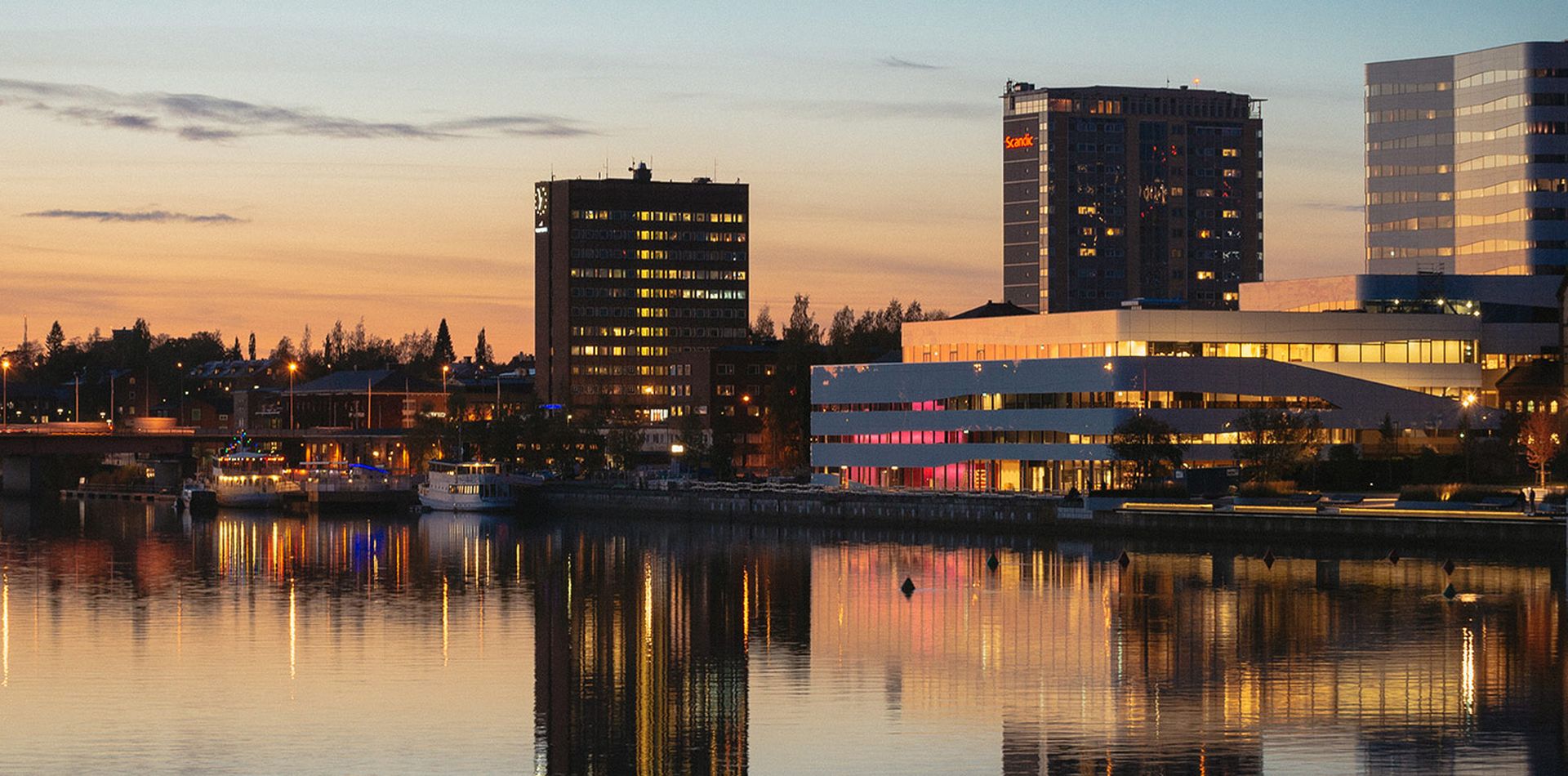 Umeå stad i skymningen. Man ser älven, tegsbron, thulehuset, väven och rådhuset.