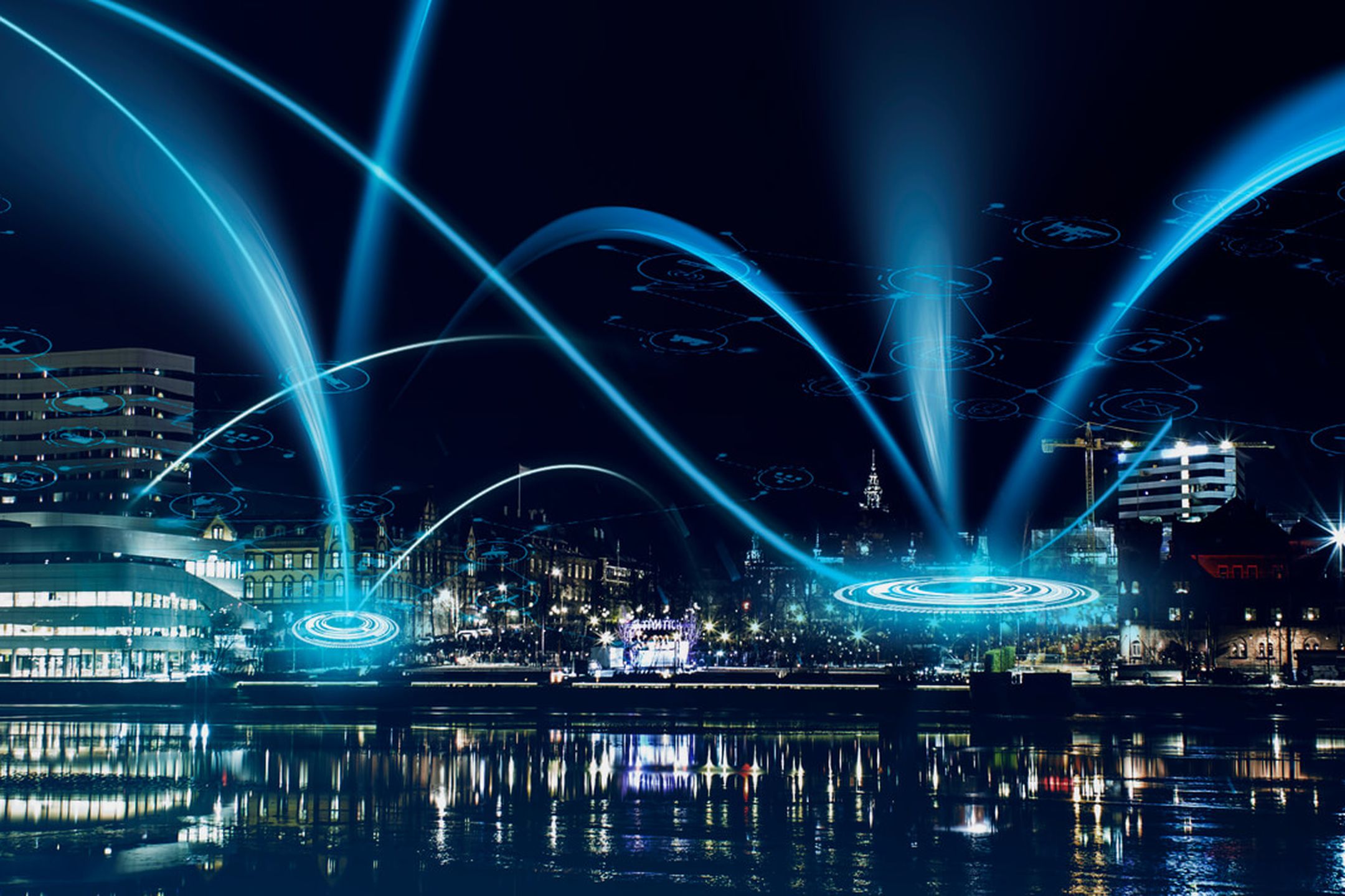 Bild som visar en vy över stadskärnan i Umeå sett från älven. Blå illustrationer som visar hur signaler skickas i ett trådlöst nätverk.