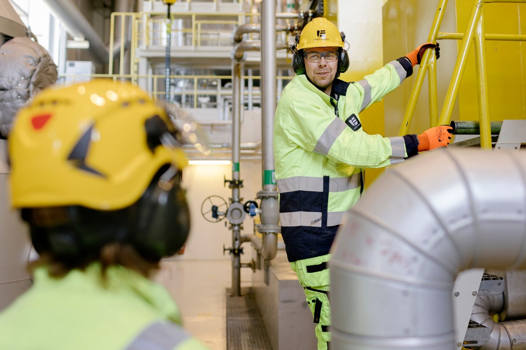 Två personer med skyddsutrustning arbetar i industrilokal