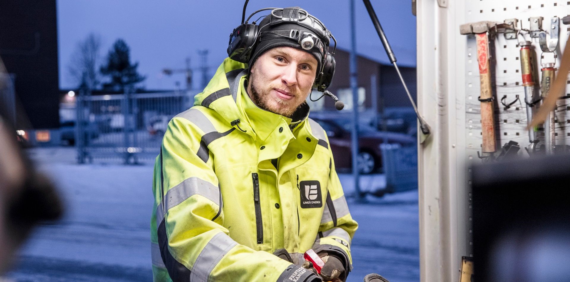 Man klädd i varselkläder ler och arbetar vid ett förråd, utomhus