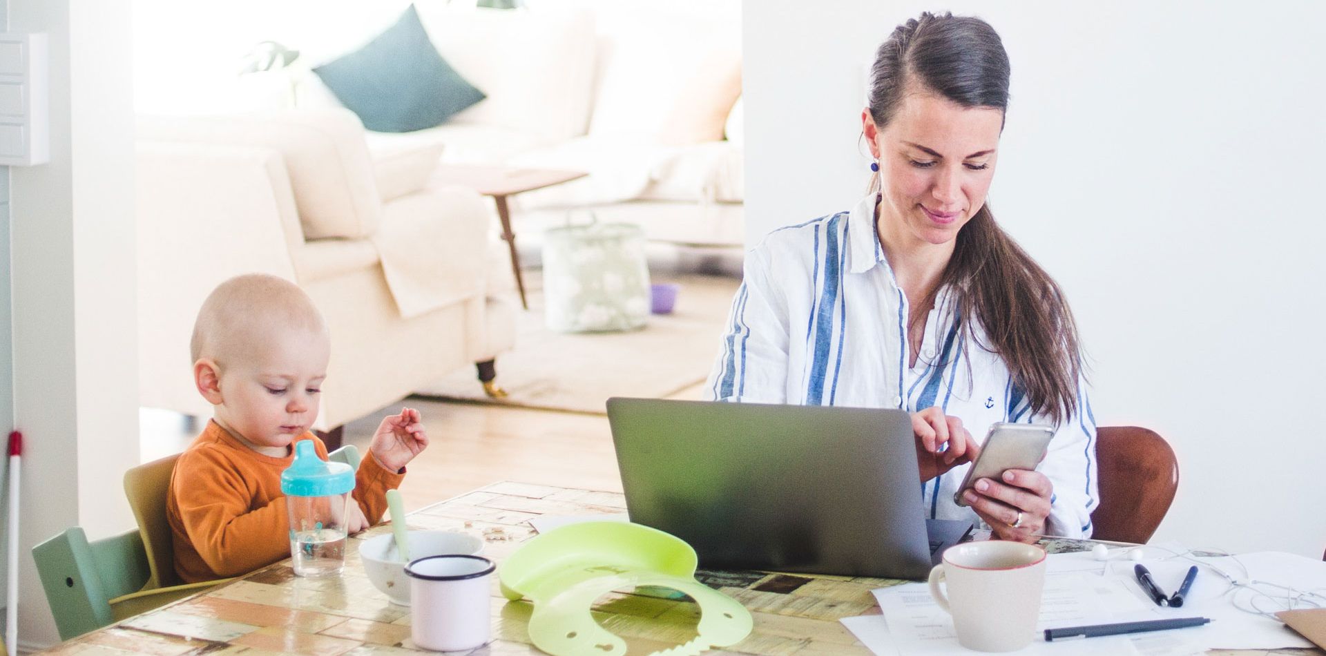 Person arbetar samtidigt som hen tar hand om sitt barn i sitt hemmakontor