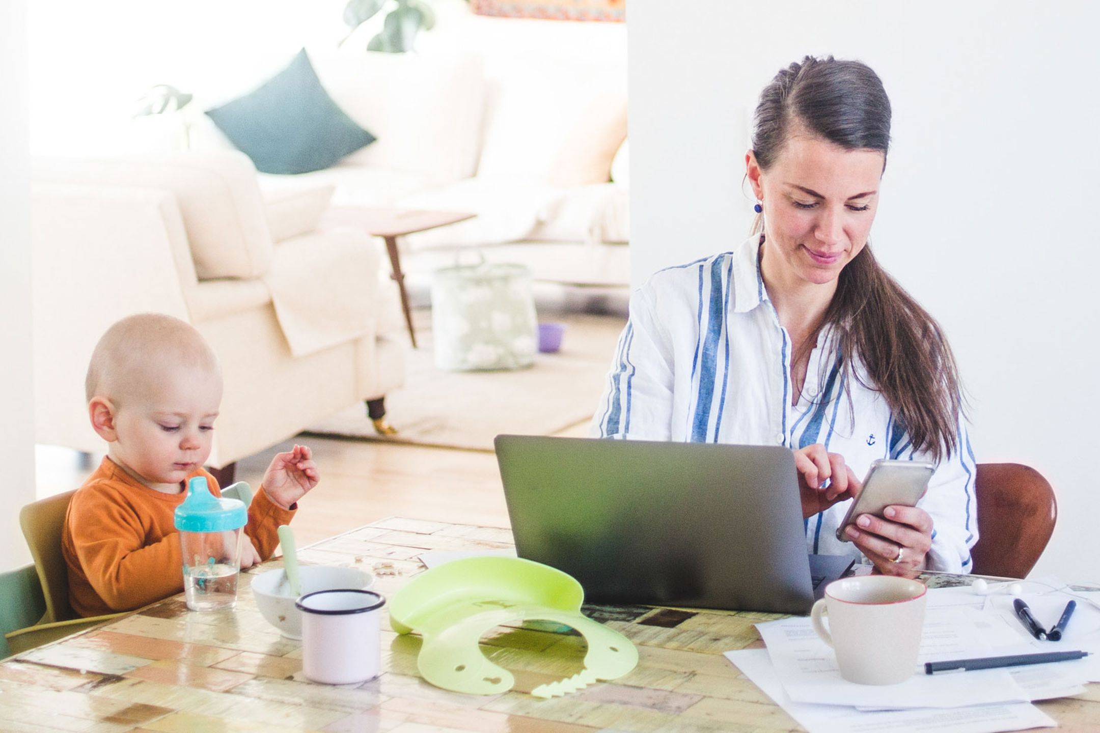 Person arbetar samtidigt som hen tar hand om sitt barn i sitt hemmakontor