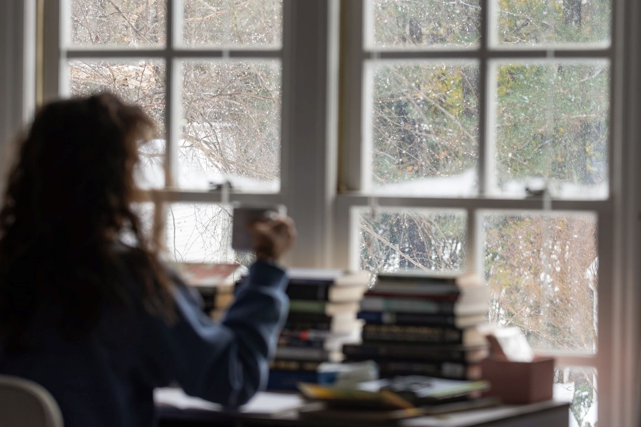 Person sittandes vid ett skrivbord som tittar ut genom ett fönster