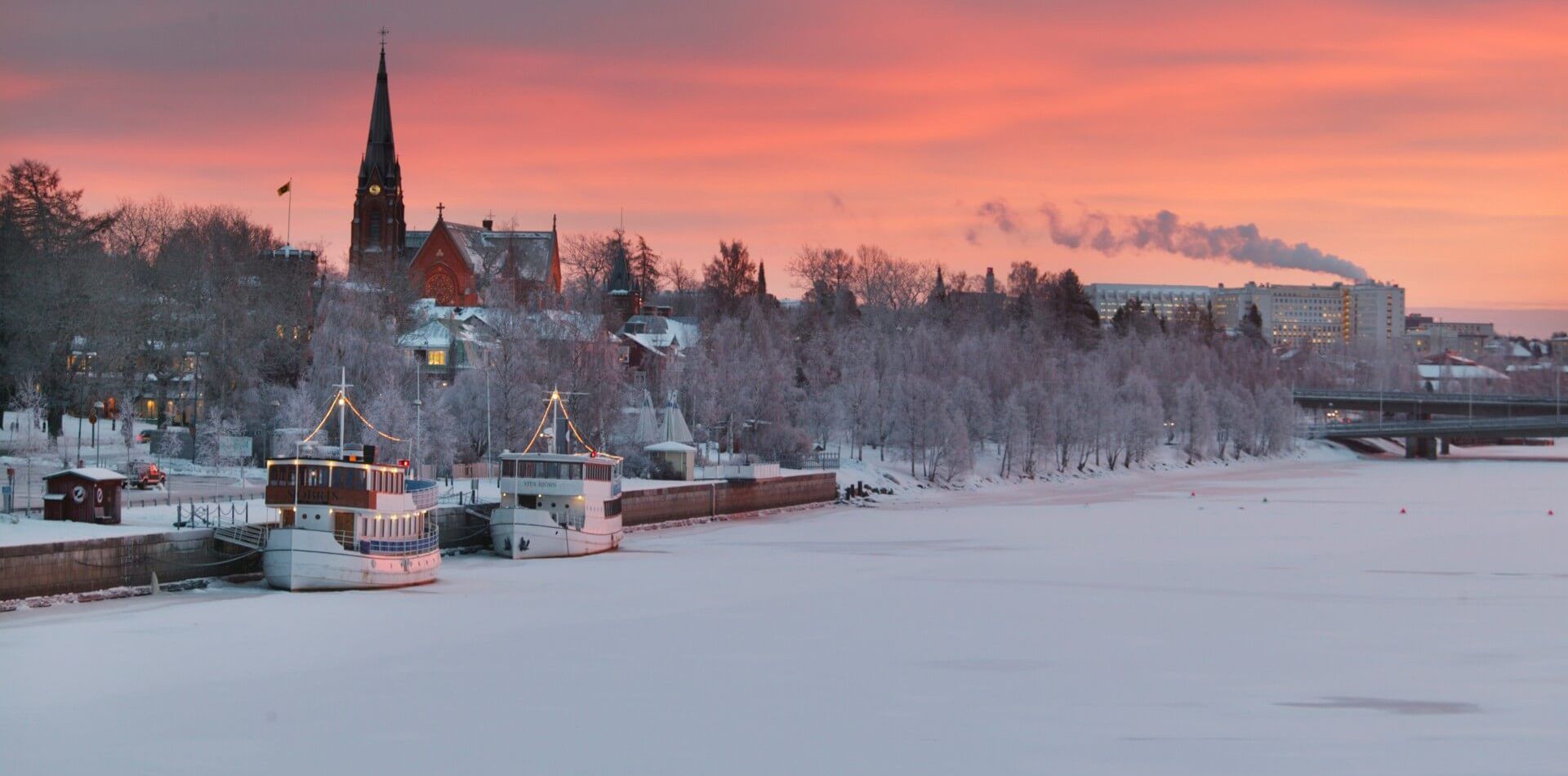 Kajen i Umeå en vinterdag med restaurangbåten Sjöbris och cafébåten Vita Björn. Stadskyrkan syns i bakgrunden