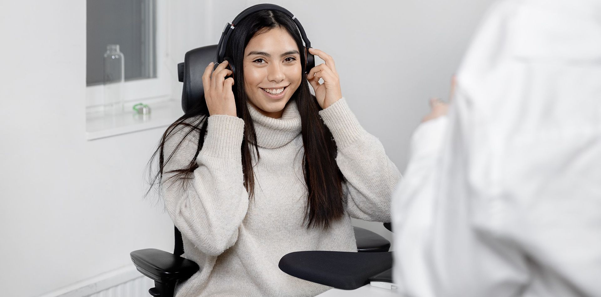 Porträtt av person med headset sittande vid skrivbord i kontorsmiljö