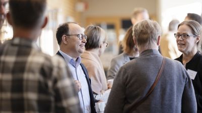 En bild av flera glada, leende människor vid ett evenemang  stående och pratar med varandra