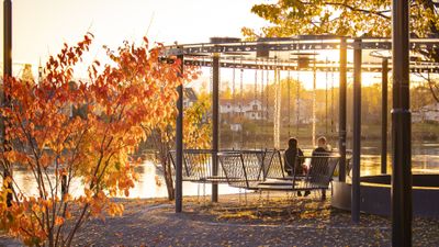 Två personer sitter i en gunga i en av Umeås parker