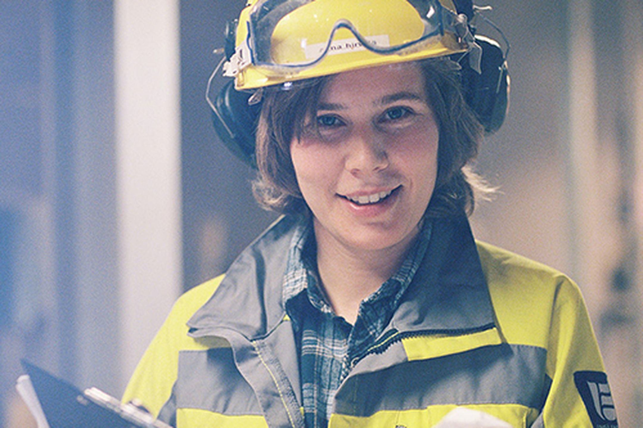 Kvinna klädd i varselkläder ler glatt