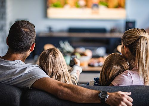 En familj som sitter i soffan framför en tv