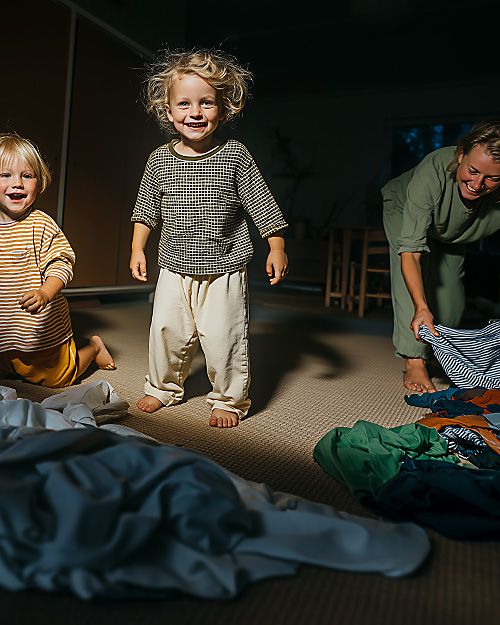 AI-genererad bild där två barn hoppar i en hög av kläder.