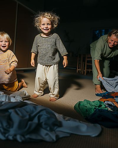 AI-genererad bild där två barn hoppar i en hög av kläder.