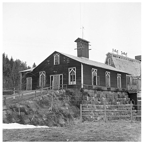 En historisk bild i svartvitt av hur Klabböle kraftverk såg ut år 1899. Byggnaden är i trä.